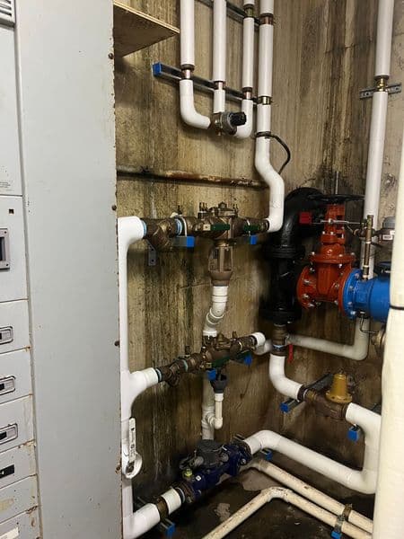 Complex plumbing setup with various valves and pipes in a utility space.
