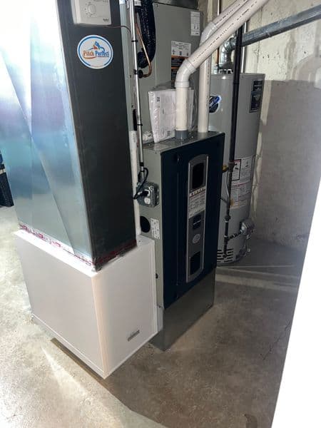 Modern heating system installation in a basement, featuring a furnace and water heater.