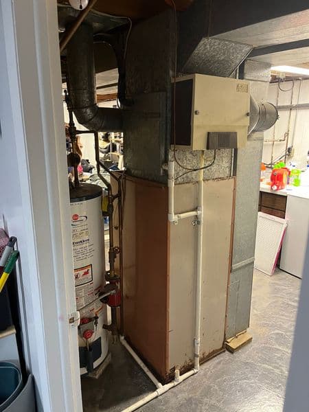 Residential basement heating system with water heater and ductwork.