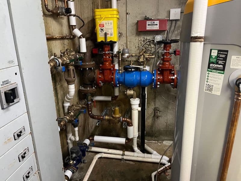 Plumbing system with pipes, valves, and a water heater in a basement utility room.