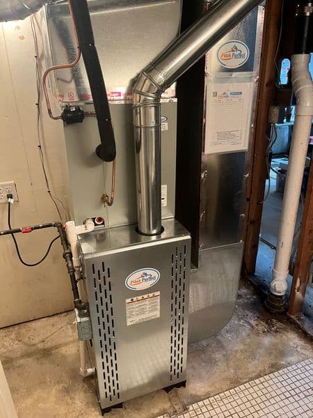 High-efficiency furnace installation in residential basement with ventilation pipe.