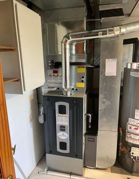 High-efficiency furnace with stainless steel venting in a residential utility room.
